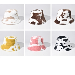 Fuzzy cow print bucket hat set in six colors including pink yellow and brown