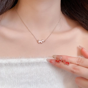 Detail of rose gold Scottish Terrier necklace and red enamel stud earrings on model