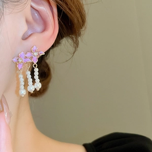 Detail view of purple enamel flower earrings with sparkling zircons and pearl tassels