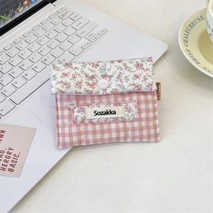 Pink floral and plaid fabric sanitary pad pouch with heart button near a laptop