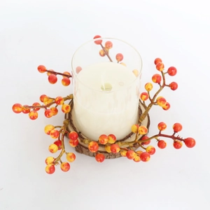 Macro view of a glass candle holder with autumn orange berries and a rustic wood base