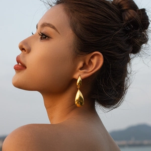 Minimalist gold teardrop earrings for women in polished finish worn by a model at sunset