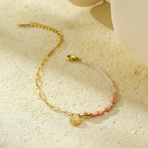 Detail of pink beaded and gold chain bracelet with a sparkling crystal sun pendant
