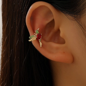 Macro shot of hummingbird ear cuff featuring gold metal and vibrant zircon stones