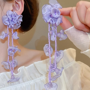 Detail view of purple chiffon flower earrings with long beaded tassels on model