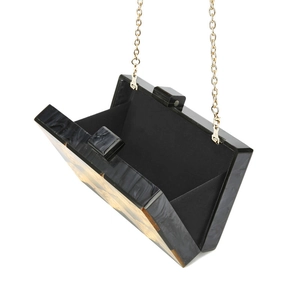 Detail of acrylic evening clutch bag showing the marble texture and gold chain strap
