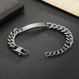 Close-up of men's steel Cuban chain bracelet with a blank ID plate on black leather