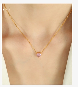 Close-up of pink heart-shaped crystal pendant necklace worn by a female model