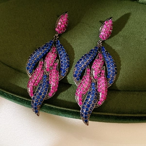 Macro shot of leaf-shaped drop earrings with pink and blue zircons in a jewelry box