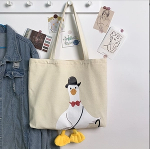 Detail of canvas tote bag with cartoon goose pattern and 3D yellow webbed feet decor
