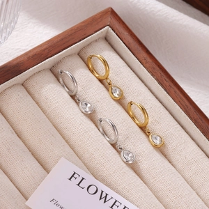 Fashionable gold and silver hoop earrings with teardrop zircon crystals on jewelry tray