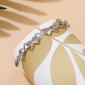 Detailed view of silver infinity chain bracelet with S-link design on cylindrical stand
