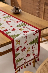 Close-up of woven Christmas table runner with reindeer motifs and festive tassels