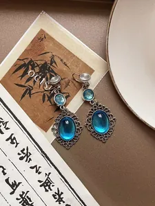 Detailed close-up of sky blue resin oval earrings with vintage silver filigree edge