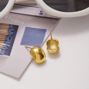 Polished gold geometric C-shaped stainless steel earrings on a lifestyle background