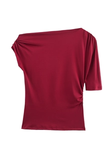 Detail of red off-shoulder asymmetric top showing pleated texture and fabric sheen