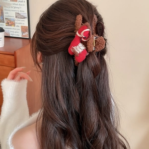 Detail of red and brown plush hair claw clip worn on a half-up hairstyle in soft lighting