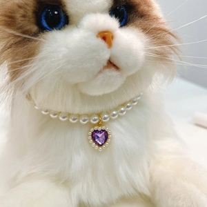 Close-up of pet pearl necklace with purple heart crystal pendant on white cat