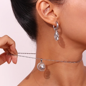 Macro shot of silver-colored sun and eye pendant with rhinestones on a woman neck