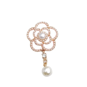 Golden camellia flower pendant with pearls and a crystal drop on a white background