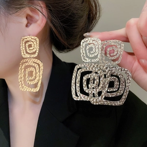 Detail of gold and silver textured square spiral earrings with hammered metal finish