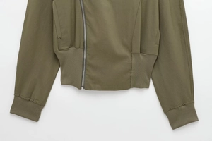 Detailed view of army green jacket featuring diagonal zipper and ribbed cuffs and hem