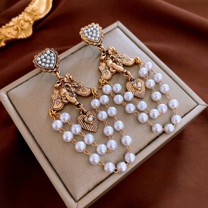 Detailansicht von Vintage-Ohrringen mit Perlenherzen und Engel-Quasten-Details