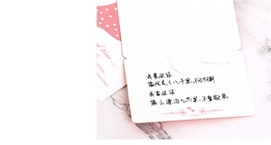 Close-up of a white greeting card with pink polka dots and handwritten love poem detail