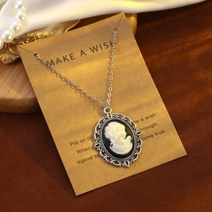 Vintage silver cameo necklace with white silhouette on paper card with pearls and gold tray