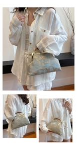 Detail of light blue satin handbag with gold floral embroidery and wooden handle