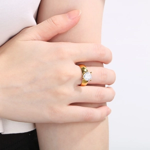 Close-up of 18K gold plated ring with round white zircon on finger for wedding