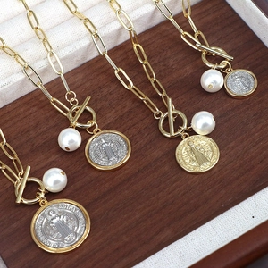 Detail of four gold necklaces with toggle clasps and Saint Benedict medal pendants