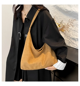 Close-up of a large brown suede tote bag featuring a minimalist crescent moon shape and strap