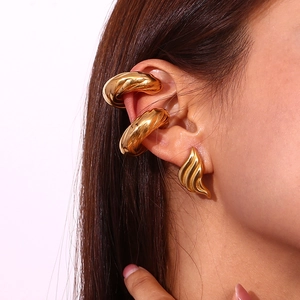 Polished 18K gold hollow triangle earrings and twisted cuff earrings on woman ear