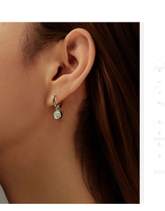 Detail view of a 6.5mm round moissanite drop earring on a model ear in silver finish