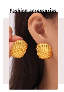 Detail showing vintage gold oval earrings with vertical embossed texture on model