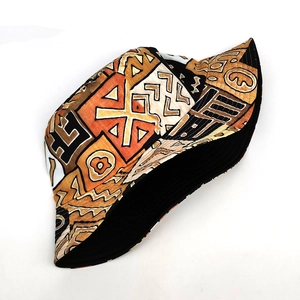 Détail d'un chapeau bob bohème avec des motifs géométriques tribaux en orange et noir