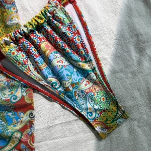 Detail of paisley print bikini bottom with elastic ruched waist and red edge stitching