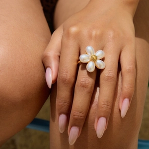 Elegant gold flower ring with white mother of pearl petals on woman's hand
