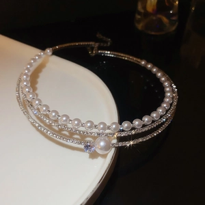 Close-up of layered choker with white pearls and sparkling diamond accents on silver chains