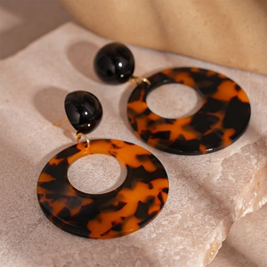 Macro shot of tortoiseshell resin hoop earrings on a textured stone surface