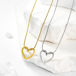 Detail of minimalist hollow heart pendants in gold and silver on sleek snake chains