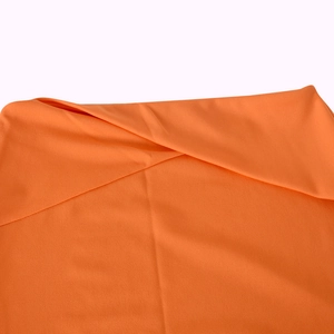 Close-up of bright orange smooth fabric texture and fine weave on a two-piece dress