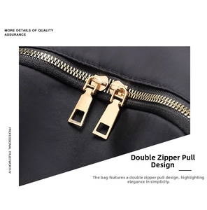 Detail of smooth double gold-tone metal zippers on water-resistant black nylon backpack