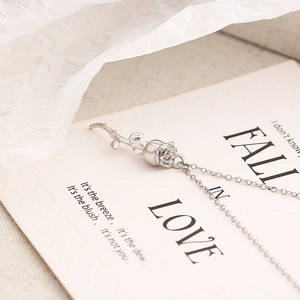 Gros plan d'un pendentif rose 3D en argent posé sur une carte poétique