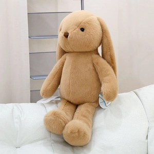 Close-up of soft fluffy long-eared rabbit plush toy sitting on a cozy grey sofa