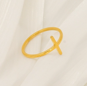 Detailed side view of 18K gold cross ring resting on elegant warm white pleated silk
