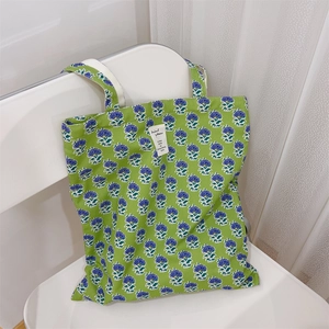 Dettaglio della borsa tote in tela verde con fiori viola e etichetta decorativa