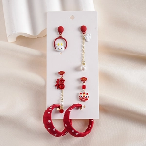 Close-up of three pairs of festive red earrings with lion dance and Fu character elements