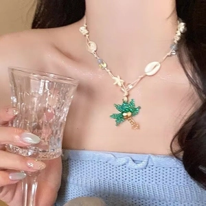 Detail of beaded coconut tree pendant on shell necklace worn for summer beach vacation